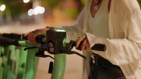 Woman's hands activating a shared electric scooter at night Stock Footage 342744276
