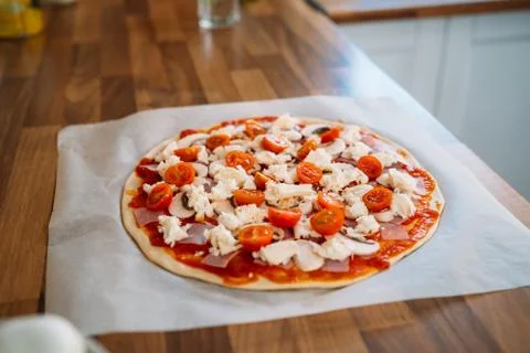 Woman's hands adding cherry tomatoes to a traditional margarita pizza. Prepar Stock Photos