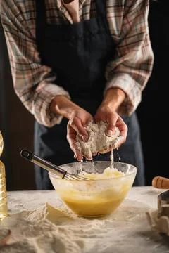 Woman's hands adding flour to a bowl of batter with a whisk inside. Baking pr Stock Photos