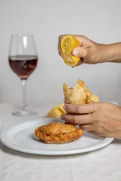 Woman's hands adding lemon to an Argentine empanada. Stock Photos