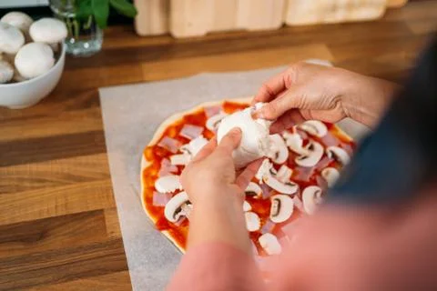 Woman's hands adding mozzarella cheese to a traditional margarita pizza. Prep Stock Photos