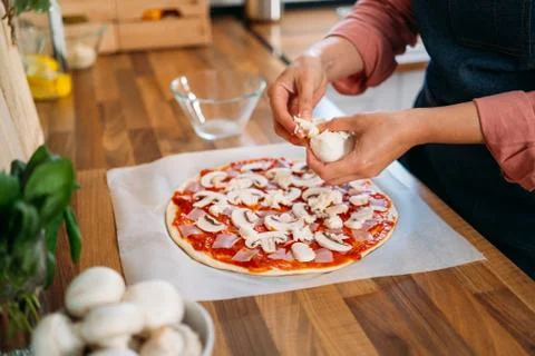 Woman's hands adding mozzarella cheese to a traditional margarita pizza. Prep Stock Photos