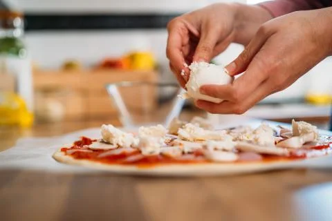 Woman's hands adding mozzarella cheese to a traditional margarita pizza. Prep Stock Photos