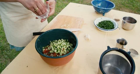 Woman's hands adding salt to fresh Tabbouleh salad Stock Footage 119846584