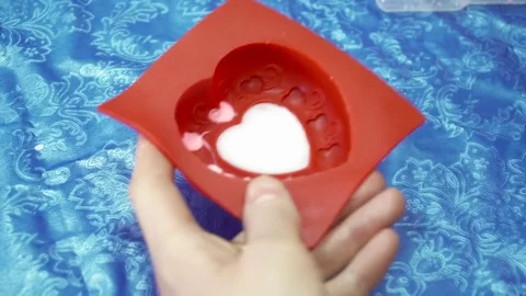 Woman's hands adding soap base to the heart template with dropper Stock Footage 74360302