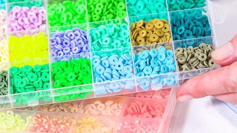 Woman's Hands Amidst a Rainbow Array of Beads for Jewelry Crafting Fotos de archivo