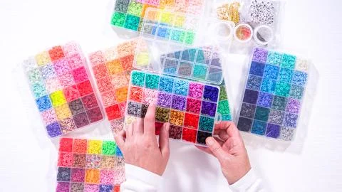 Woman's Hands Amidst a Rainbow Array of Beads for Jewelry Crafting Fotos de archivo