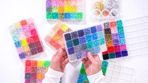Woman's Hands Amidst a Rainbow Array of Beads for Jewelry Crafting Fotos de archivo