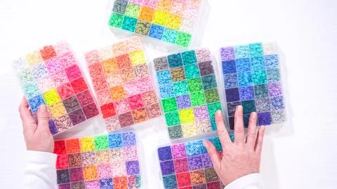 Woman's Hands Amidst a Rainbow Array of Beads for Jewelry Crafting Fotos de archivo