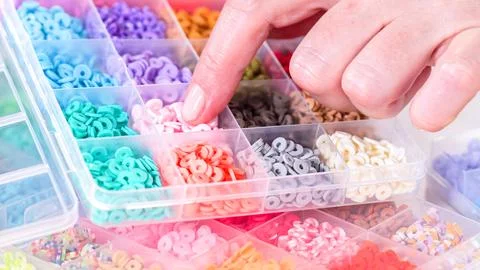 Woman's Hands Amidst a Rainbow Array of Beads for Jewelry Crafting Fotos de archivo