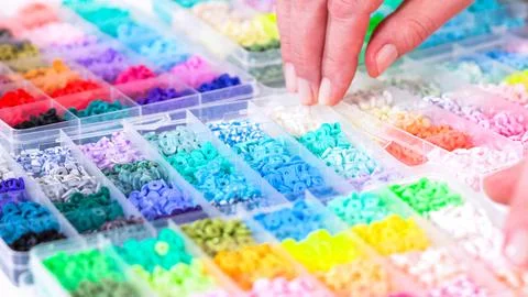 Woman's Hands Amidst a Rainbow Array of Beads for Jewelry Crafting Fotos de archivo