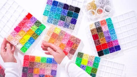 Woman's Hands Amidst a Rainbow Array of Beads for Jewelry Crafting Fotos de archivo