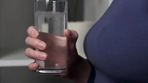 Woman's hands applying effervescent tablet into a drinking glass Stock Footage 260514298