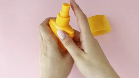 Woman's hands applying sunscreen or suntan lotion from a yellow spray bottl.. Vídeos de archivo 335139250