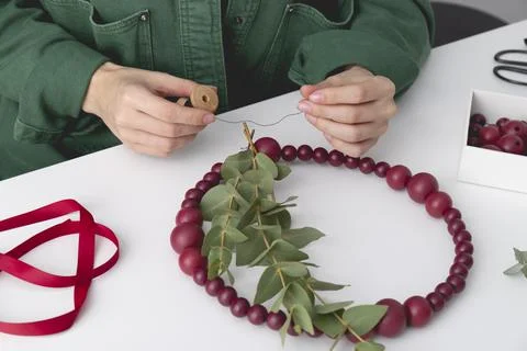 Woman's hands are adding the eucalyptus to the decorative wreath made of beads Stock Photos