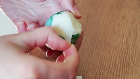 Woman's hands are cleaning a boiled Easter egg. Stock Footage 151819413