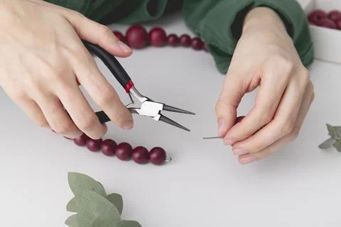 Womans hands are locking the wire on a decorative wreath. Close up. Stock Photos