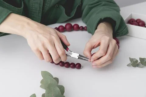 Womans hands are locking the wire on a decorative wreath. Stock Photos