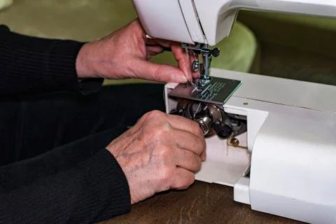 The woman's hands are replacing the spool of thread in the sewing machine. Foto stock