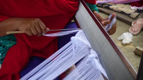 A woman's hands attach the yarn parallel to the steel thread for cloth weaving. Video stock 243300232