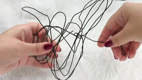 A womans hands bend a metal wire. Handiwork. Repair. Stock Footage 314307403