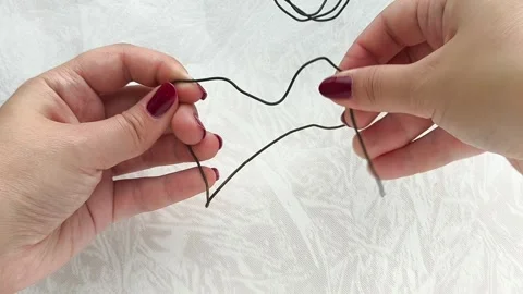 A womans hands bend a metal wire. Handiwork. Repair. Stock Footage 314307473