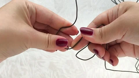 A womans hands bend a metal wire. Handiwork. Repair. Stock Footage 314307501