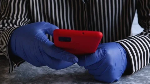 Woman's hands in blue protective gloves typing text messages on smartphone Stock Footage 127847752