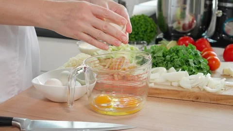 Woman's hands breaking eggs into a glass measuring cup Stock Footage 263155803