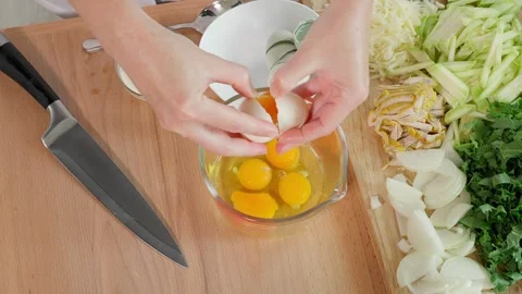 Woman's hands breaking eggs into a glass measuring cup Stock Footage 263155808