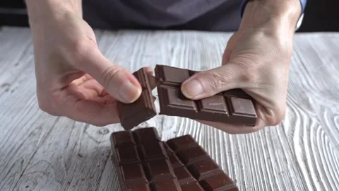 A woman's hands breaking milk chocolate into cubes. Close-up. Stock Footage 321454169