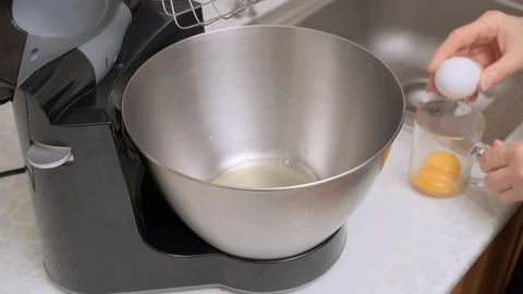 Woman's hands breaks the egg and divides the protein and yolk into the metal Stock Footage 123053296