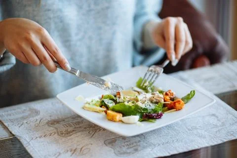 Woman's hands with Caesar salad on table in restaurant Stock Photos
