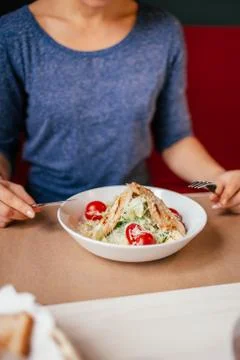 Woman's hands with Caesar salad on table in restaurant. Healthy food concept. Stock Photos