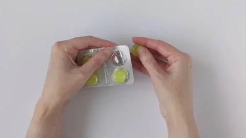 Woman's hands carefully remove a tablet from a foil blister pack Stock Footage 329479933