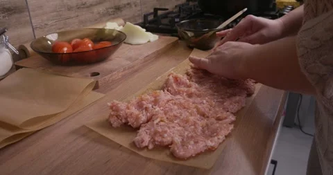 Womans hands carefully spreading raw minced meat on a sheet of parchment paper Stock Footage 329863900