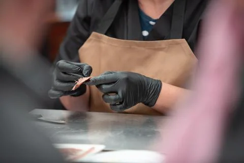Woman's hands cleaning an anchovy. Stock Photos