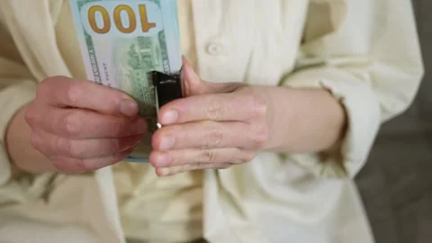 Woman's hands clipping stack of hundred dollar bills together Stock Footage 347120698