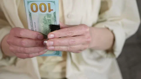 Woman's hands clipping a stack of one hundred dollar bills. Stock Footage 332982144