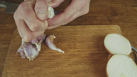 Woman's hands close up cutting onion and smashing, and peeling garlic on a Stock Footage 272794499