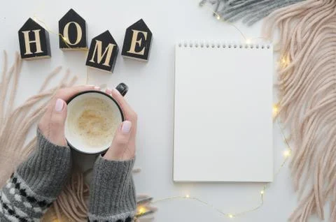 Woman's hands with coffee and notepad mockup. Stylish home desk with scarf and Stock Photos