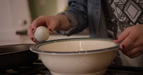 Woman's hands cracking egg on side of bowl in kitchen  Stock Footage 123737498