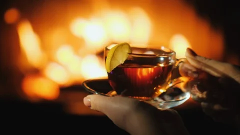 Woman's hands with a cup sat by the fireplace. Keep warm in winter concept Stock Footage 120117586