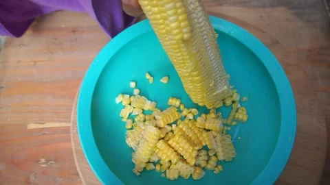 A woman's hands cut and thresh corn from the cobs using a sharp knife Stock Footage 247704928