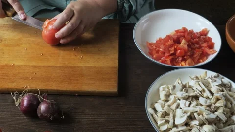 A woman's hands cut fresh red tomatoes with a knife on a cutting board on a.. 库存影片 330215133