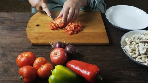 A woman's hands cut fresh red tomatoes with a knife on a cutting board on a.. 库存影片 344883951