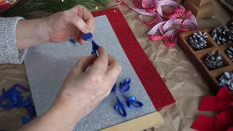 The woman's hands cut out the snowflake element from blue glitter foamiran, on Stock Footage 165190833