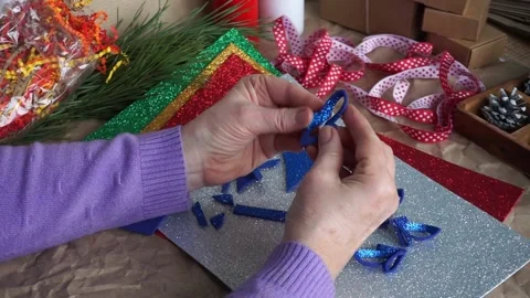 The woman's hands cut out the snowflake element from blue glitter foamiran, on Stock Footage 165264725