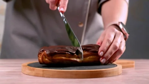 Womans hands cuts French eclair on the table. Stock Footage 267022935