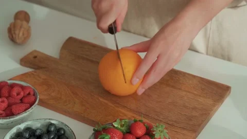 Woman's hands cuts orange on cutting wooden board Stock Footage 196629057